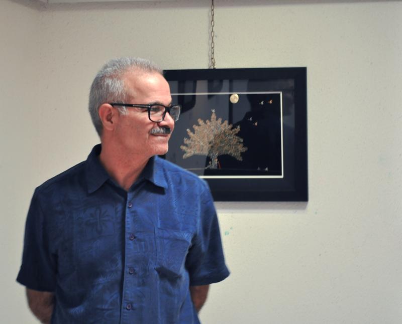 Houshang Foroutan standing beside a watch collage